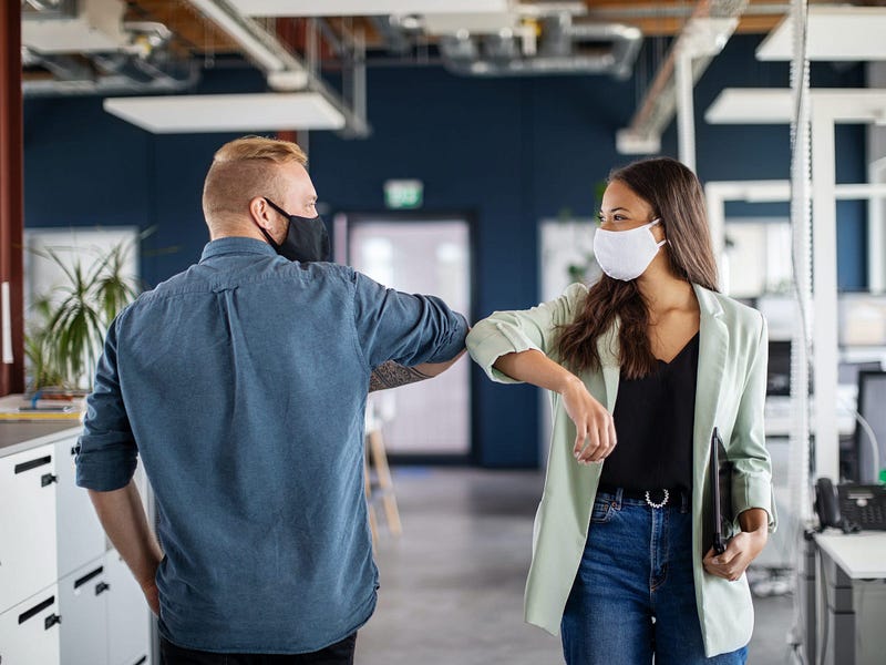 Colleagues greeting with an elbow bump in a modern office