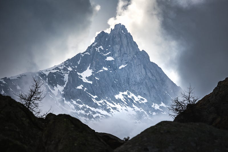 A breathtaking view of a towering mountain shrouded in clouds